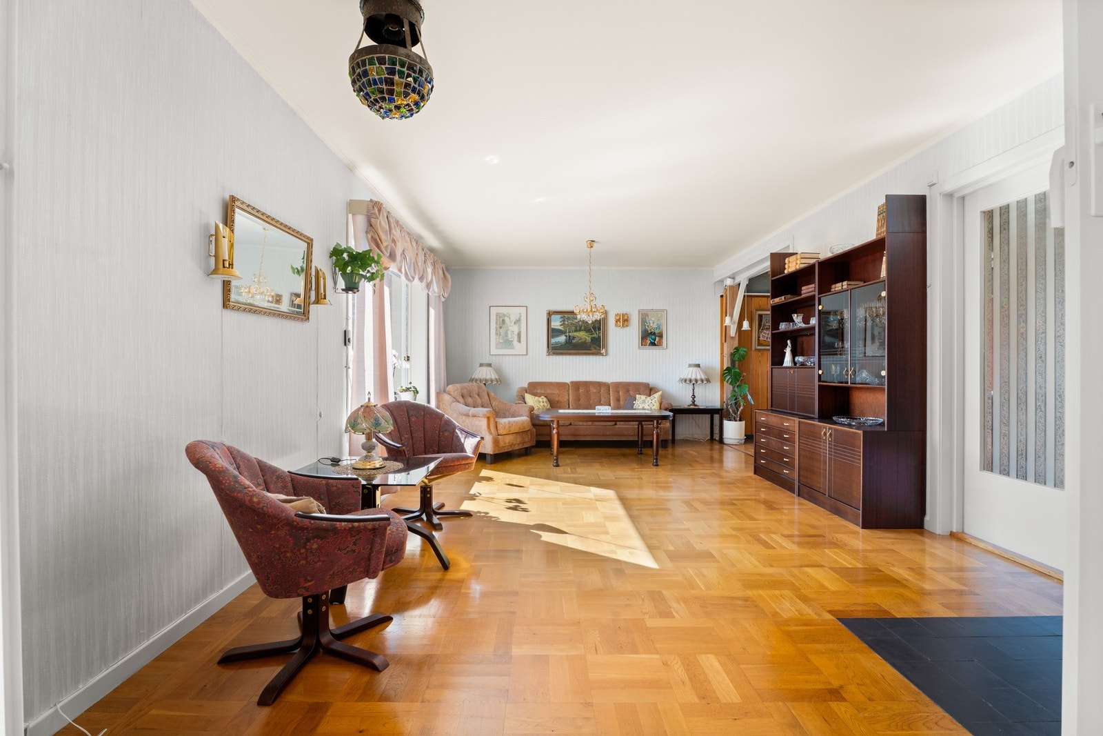 Hovedstuen ligger i midten, innredet med lys tapet, rutet parkett og hjørnepeis for ekstra hygge. Galleribilde