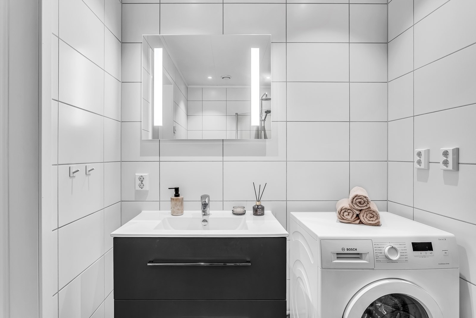 Badet er helfliset og utstyrt med servantinnredning, speil med belysning og opplegg for vaskemaskin. Galleribilde