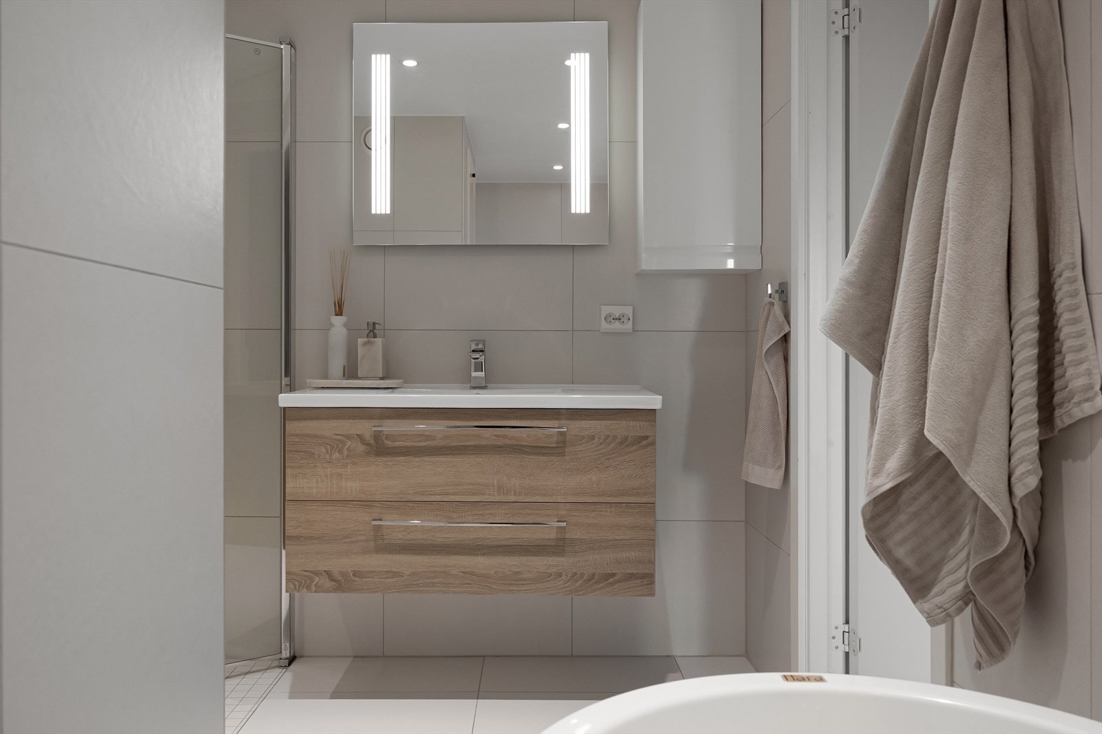 Badet er innredet med dusjsone, vegghengt toalett, badekar og servantinnredning med god oppbevaringsplass. Galleribilde