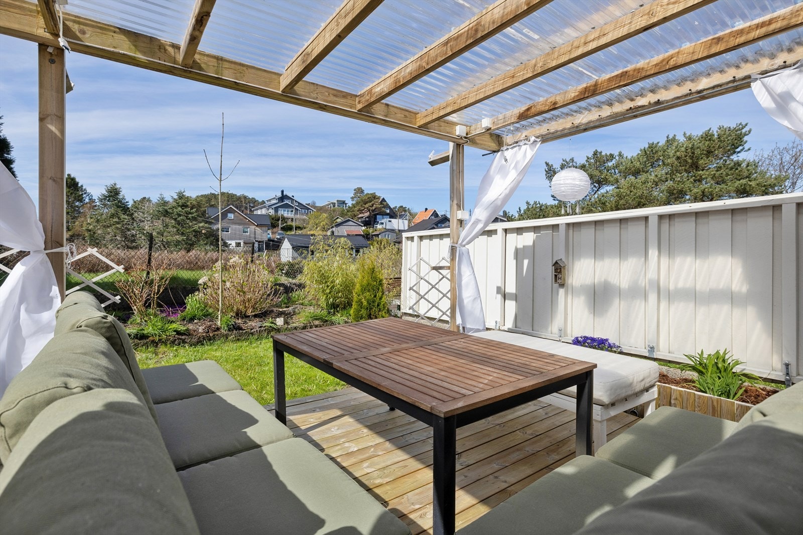 Fra soverommet kommer du ut til en hyggelig og skjermet hage bestående av plen, diverse beplantning og terrasse med pergola Galleribilde