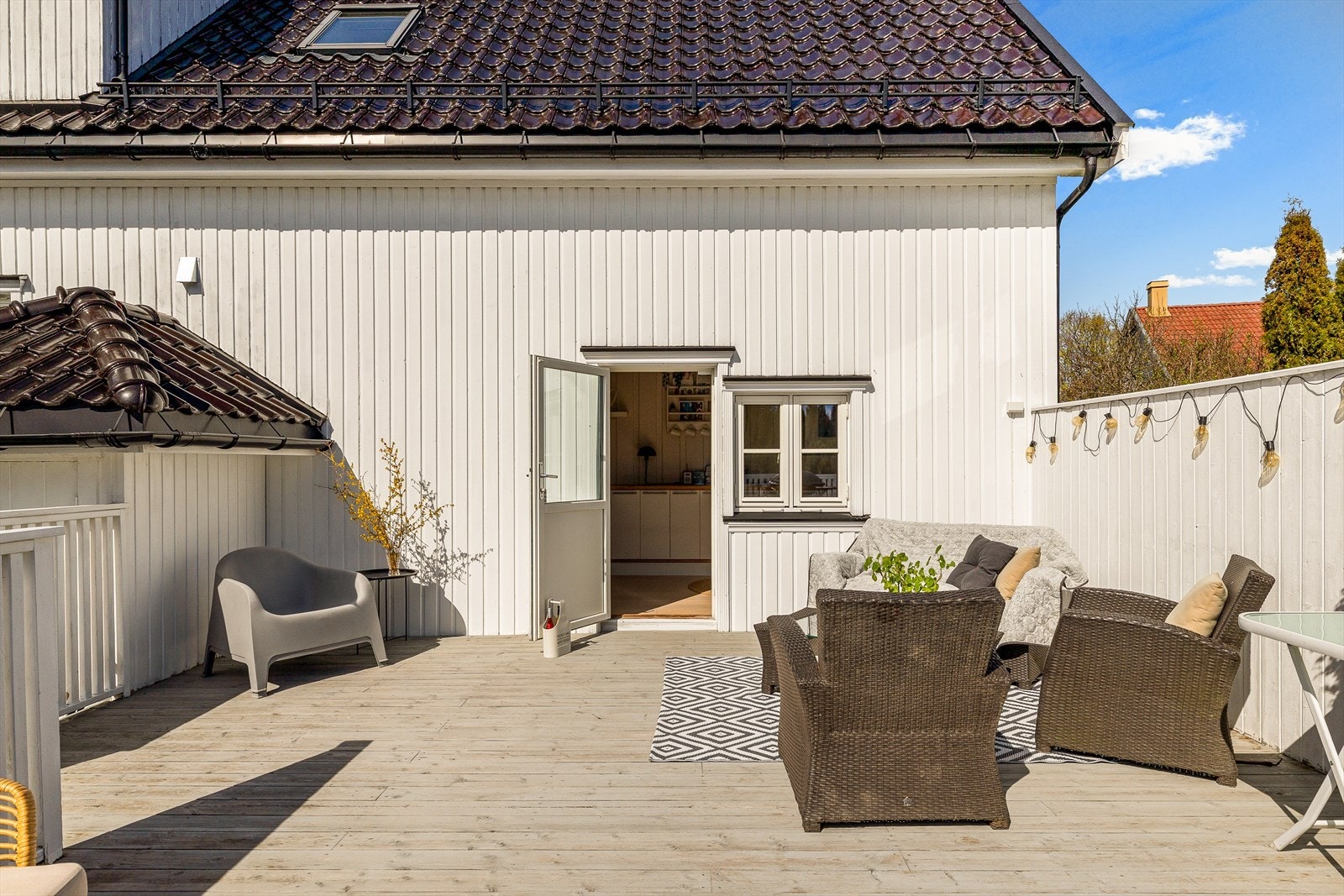 Romslig og solrik terrasse på baksiden av huset som fungerer som en naturlig forlengelse av boligens oppholdsrom. Her med utgang fra kjøkkendelen. Gode forhold for både hverdagsbruk og sosiale sammenkomster. Galleribilde