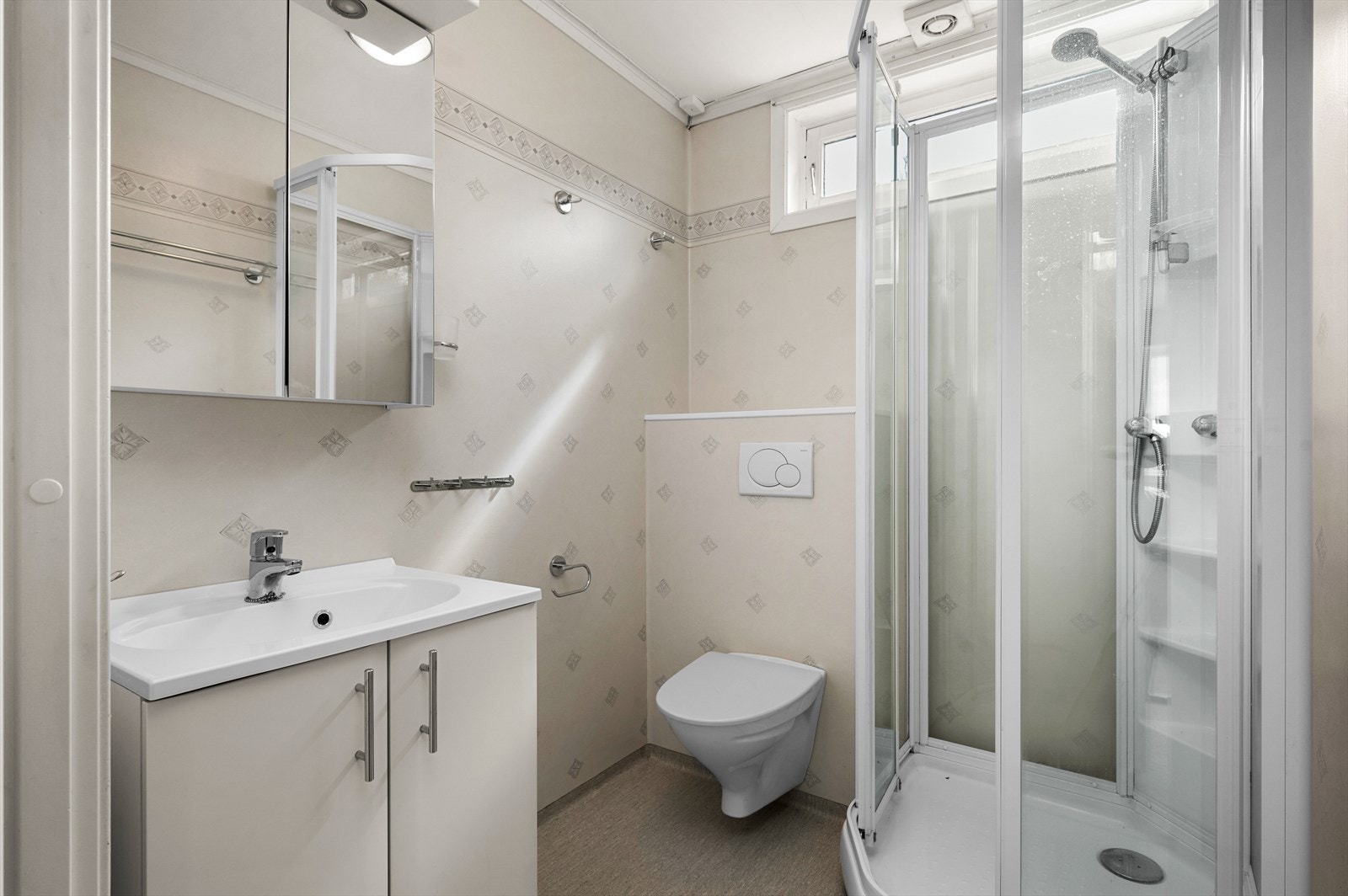 Badet måler 3,5 m² og er innredet med vegghengt toalett, dusjkabinett og gode oppbevaringsmuligheter. Galleribilde