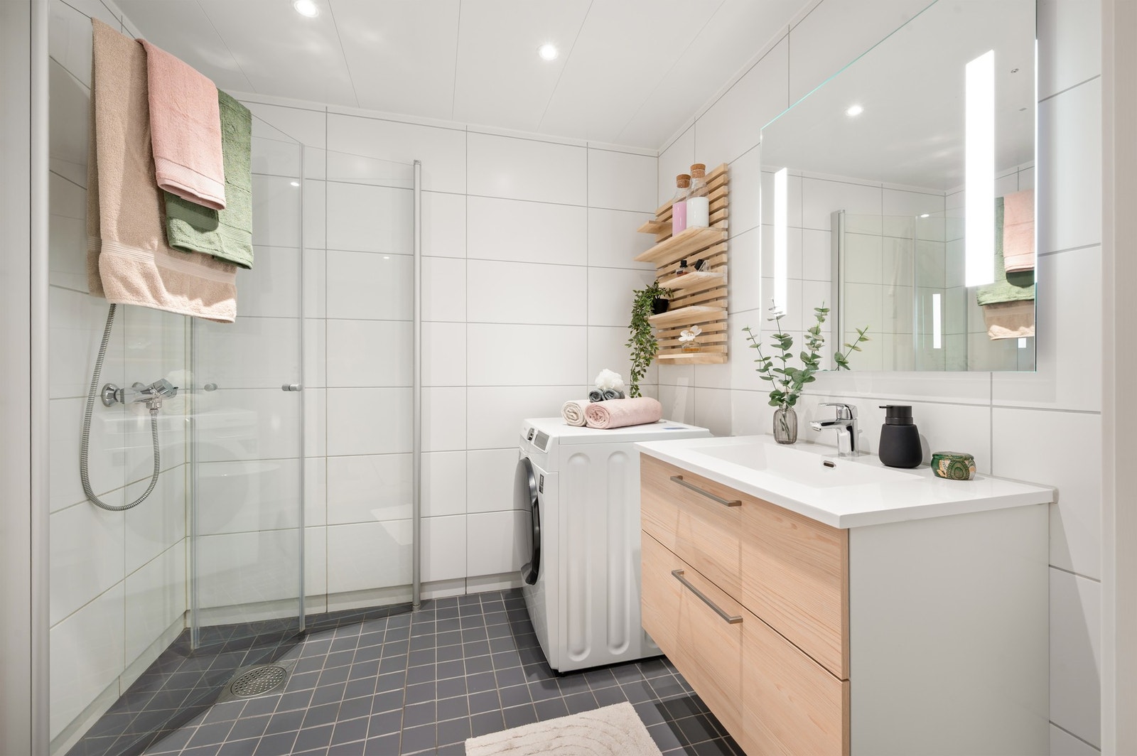 Badet er innredet med dusjhjørne, veggmontert toalett, baderomsinnredning med servant og speil. Galleribilde