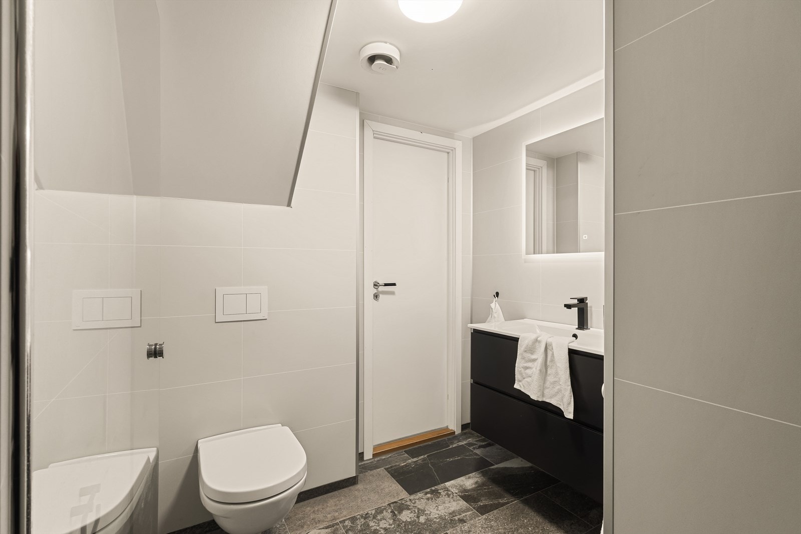 Badet har lyse baderomsplater på vegger, malt himling og flislagt gulv med varmekabler. Galleribilde