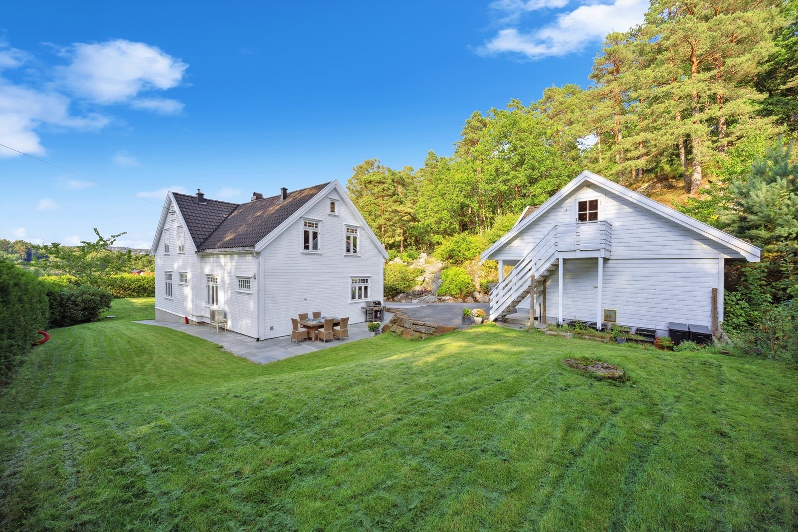 Baksiden av huset med stor hage. Utvendig trapp til loft over garasje. Galleribilde