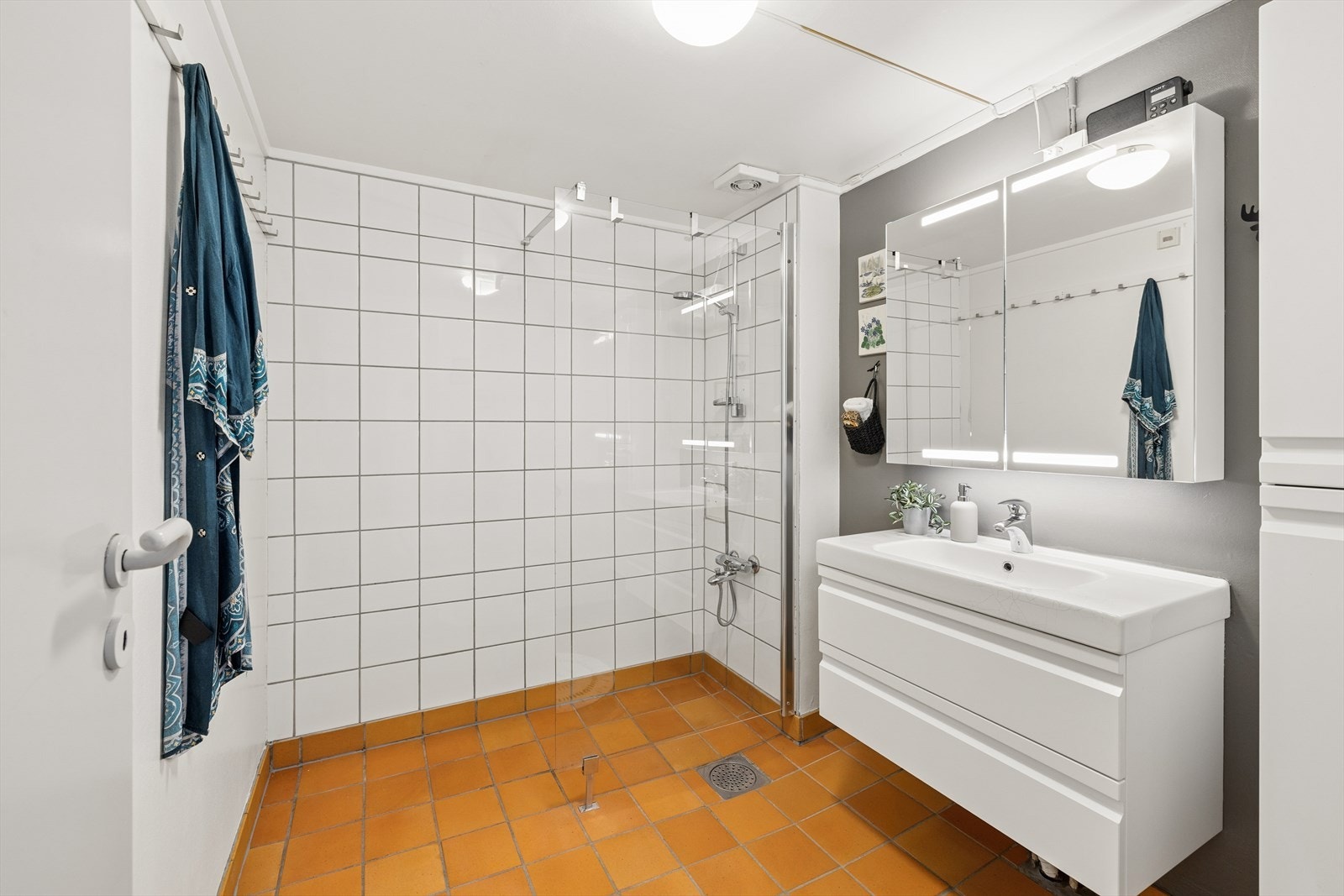 Baderommet har dusj med glassvegg, servant med skuffer og speil med lys og skapplass. Galleribilde
