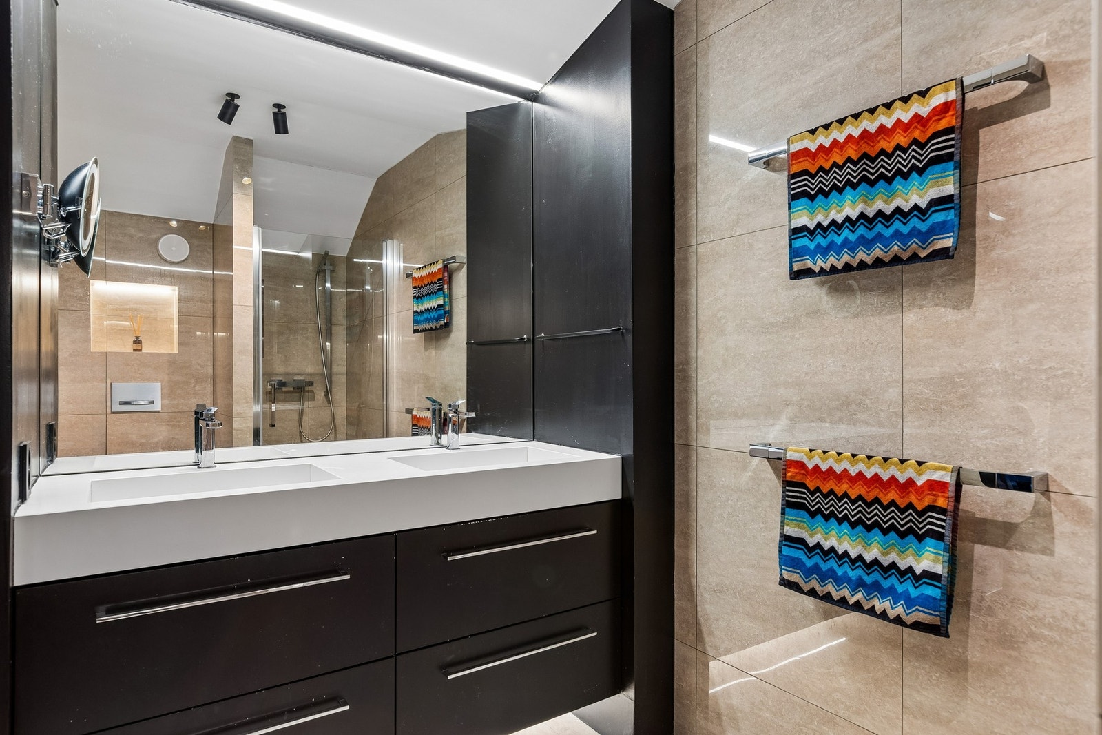 Badet på 4,5 kvm. fremstår moderne og stilrent med store 60x60 fliser på både gulv og vegger. Rommet er utstyrt med servant og servantskap, dusjnisje og veggmontert WC, samt gulvvarme som sikrer god komfort gjennom hele året. Galleribilde