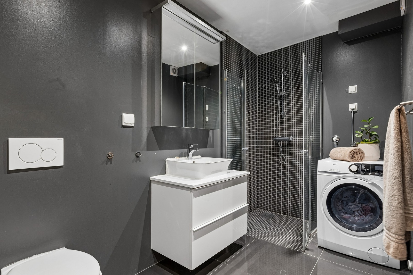 Badet er på 5 kvm. og er innredet med vegghengt servantskap, veggmontert WC, opplegg for vaskemaskin og dusjhjørne. Galleribilde