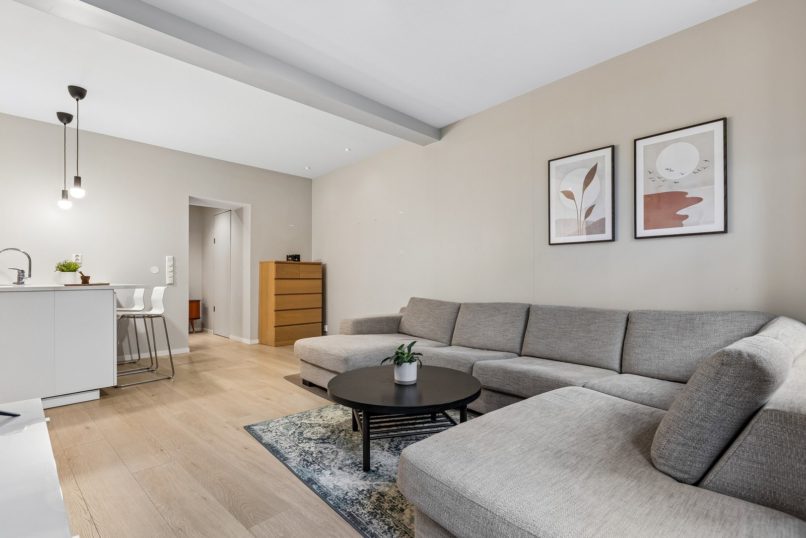 Her får du en åpen stue/kjøkken som måler 26 kvm. Laminat på gulv, og lyse, nøytrale veggflater som gir et moderne og tidløst uttrykk. Velplasserte downlights i himlingen bidrar til en behagelig og gjennomført belysning. Galleribilde