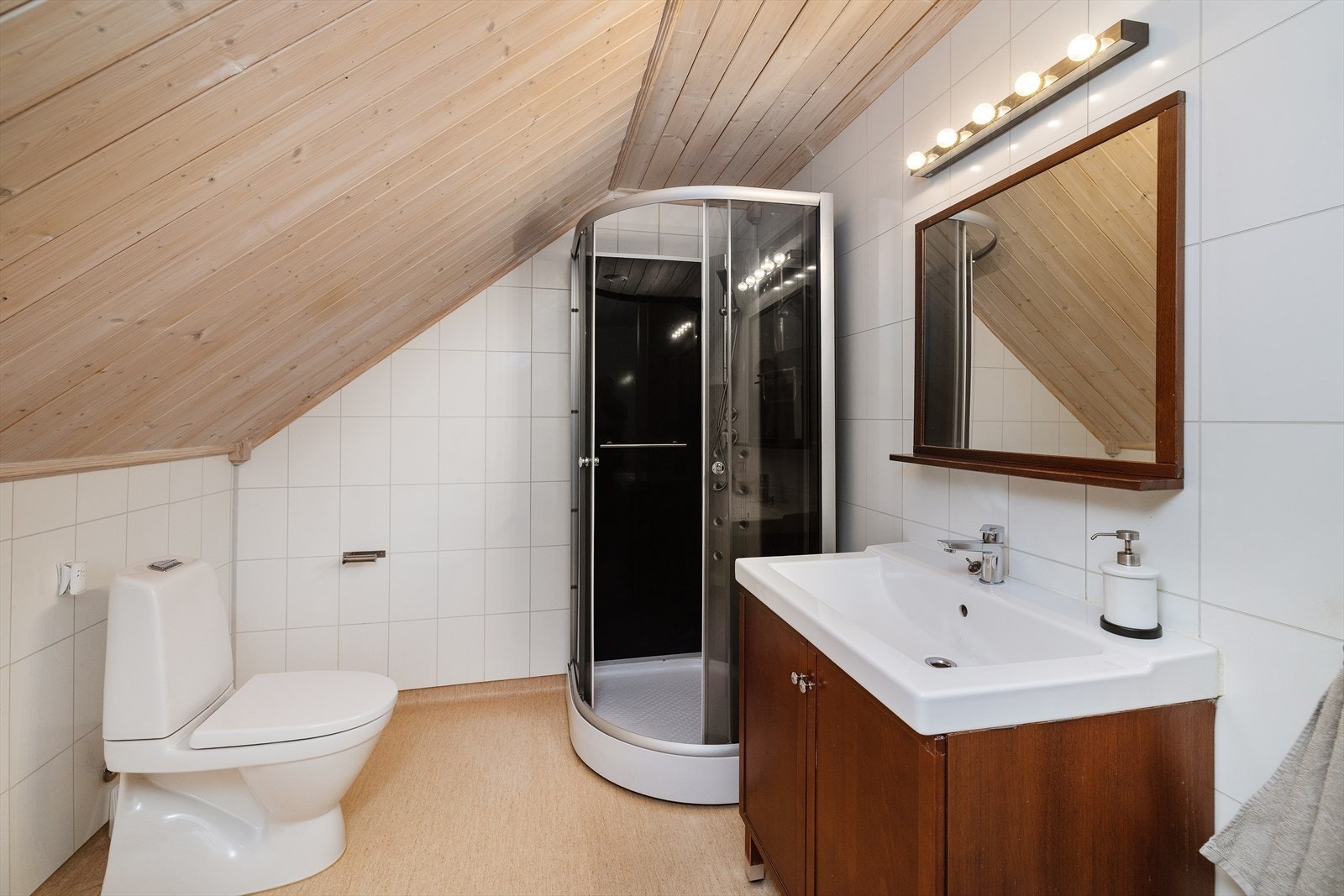 Badet i andre etasje har baderomsplater på veggene, panel i taket og vinylbelegg på gulvet. Rommet er utstyrt med dusjkabinett, toalett og servant. Galleribilde