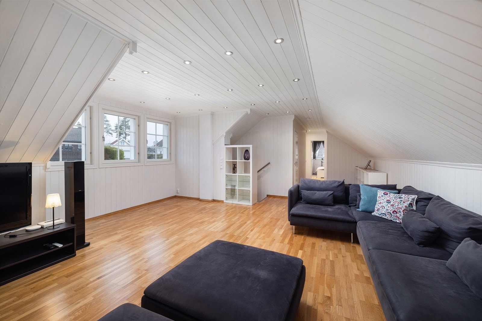 Loftstuen i andre etasje er et lyst og luftig rom med parkett på gulv samt malt trepanel i taket og god plass til en stor sofagruppe. Galleribilde