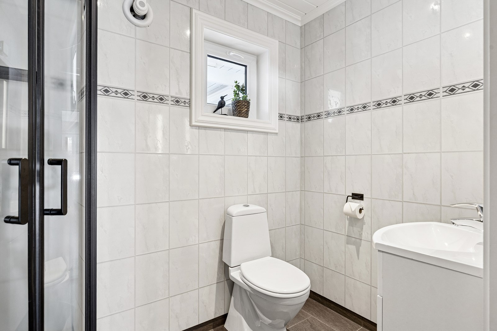 Badet har praktisk tilkomst fra hallen og er utstyrt med toalett, servantinnredning og dusjkabinett. Galleribilde
