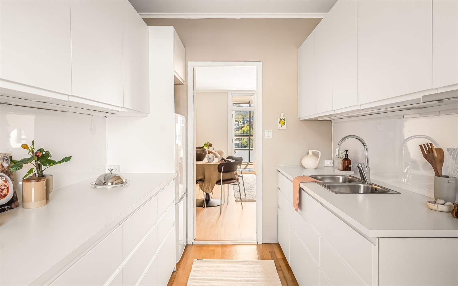 Kjøkkenet ble oppgradert med ny IKEA-kjøkkeninnredning i 2019, med slette hvite fronter som gir et tidløst uttrykk. Det er laminat benkeplate, stål vaskekum og ventilator. Over benkeplaten er det montert kitchen boards (fra 2026). Galleribilde