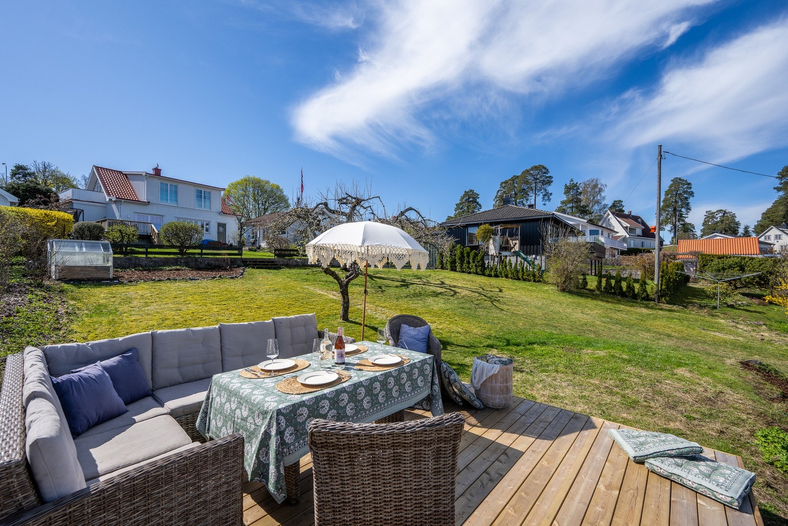 Uteområde med terrasse og plen, omgitt av hyggelig nabolag. Galleribilde