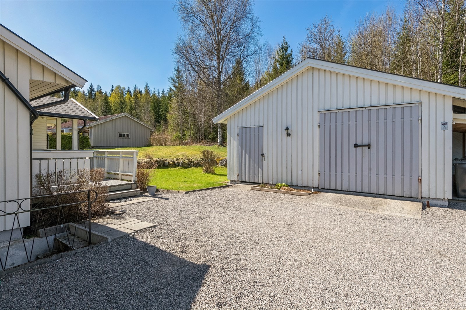 Den gruslagte innkjørselen fører frem til garasjen, som også har en enkel carport for ekstra parkering. Galleribilde
