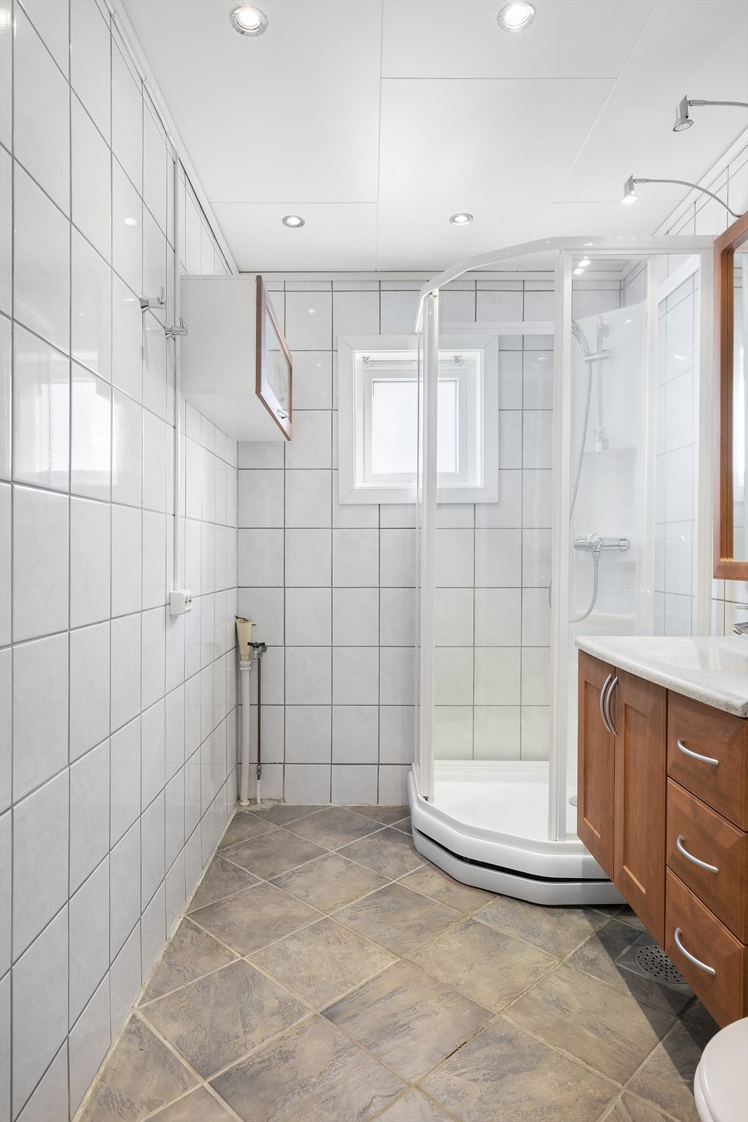 Badet har flislagte overflater og dusjkabinett, med elektriske varmekabler i gulvet. Galleribilde