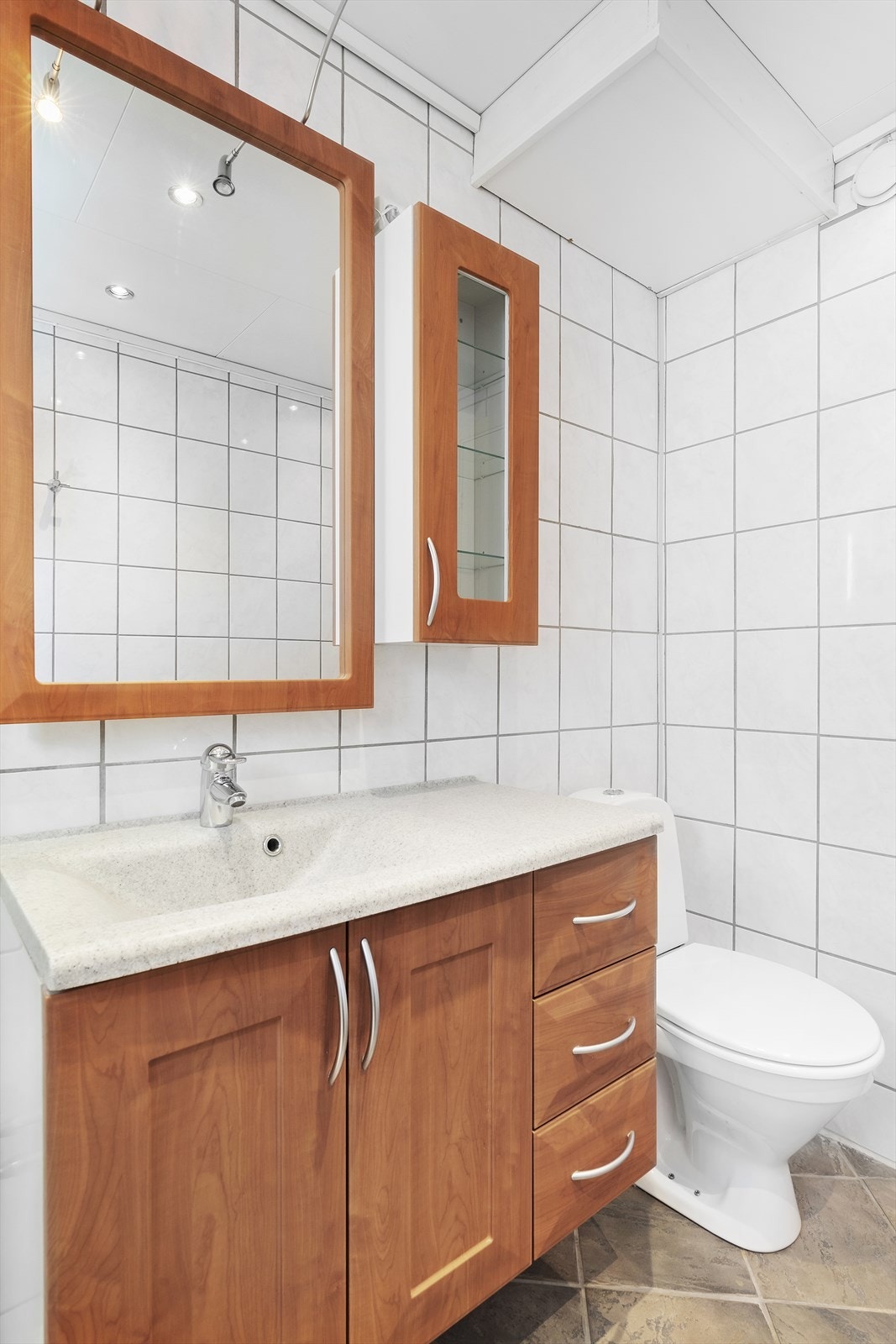 I tillegg til dusjkabinett er badet utstyrt med toalett og baderomsinnredning med heldekkende servant, profilerte fronter og speilskap. Galleribilde