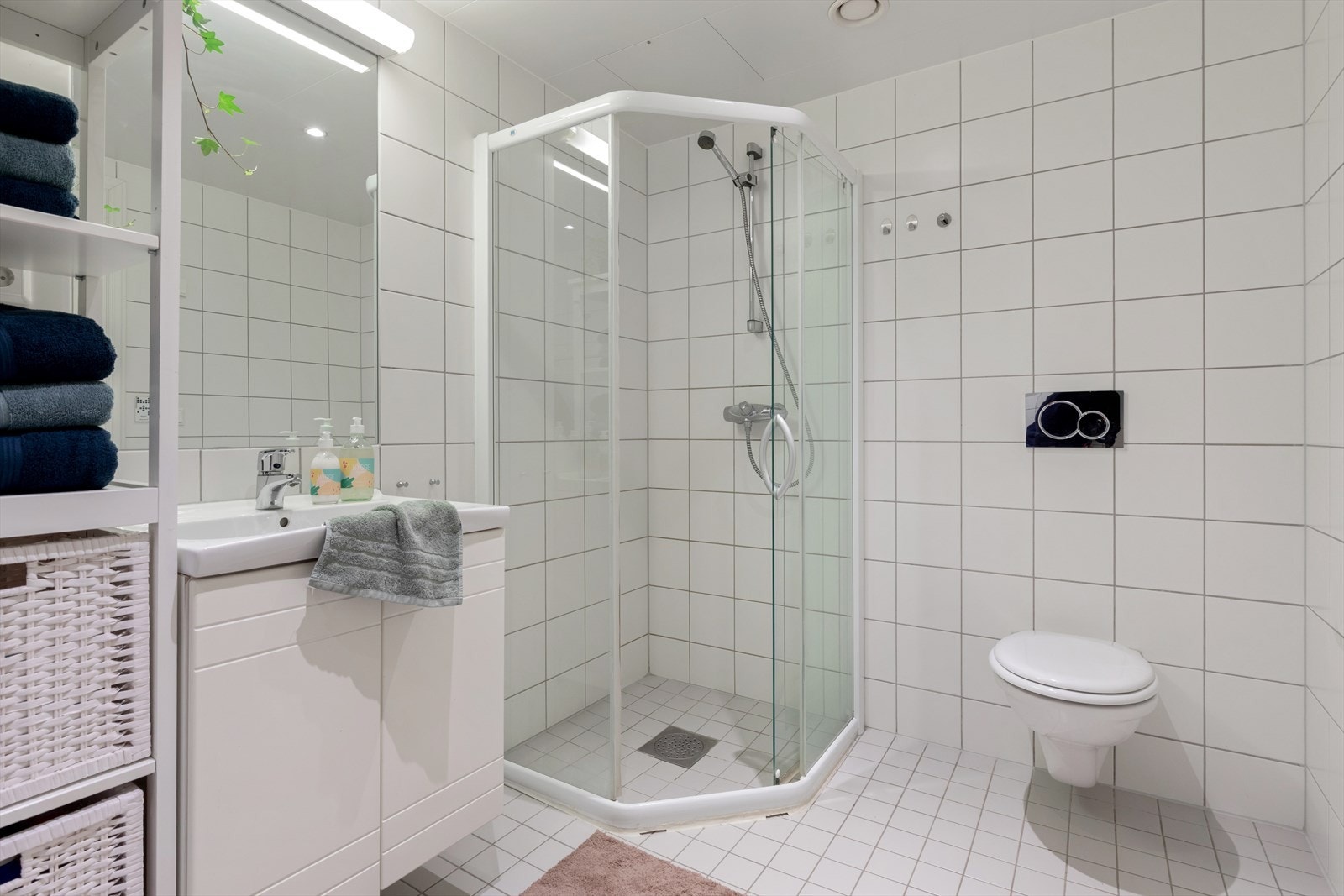 Badet er innredet med vegghengt toalett, dusjhjørne og baderomsinnredning med speil over Galleribilde