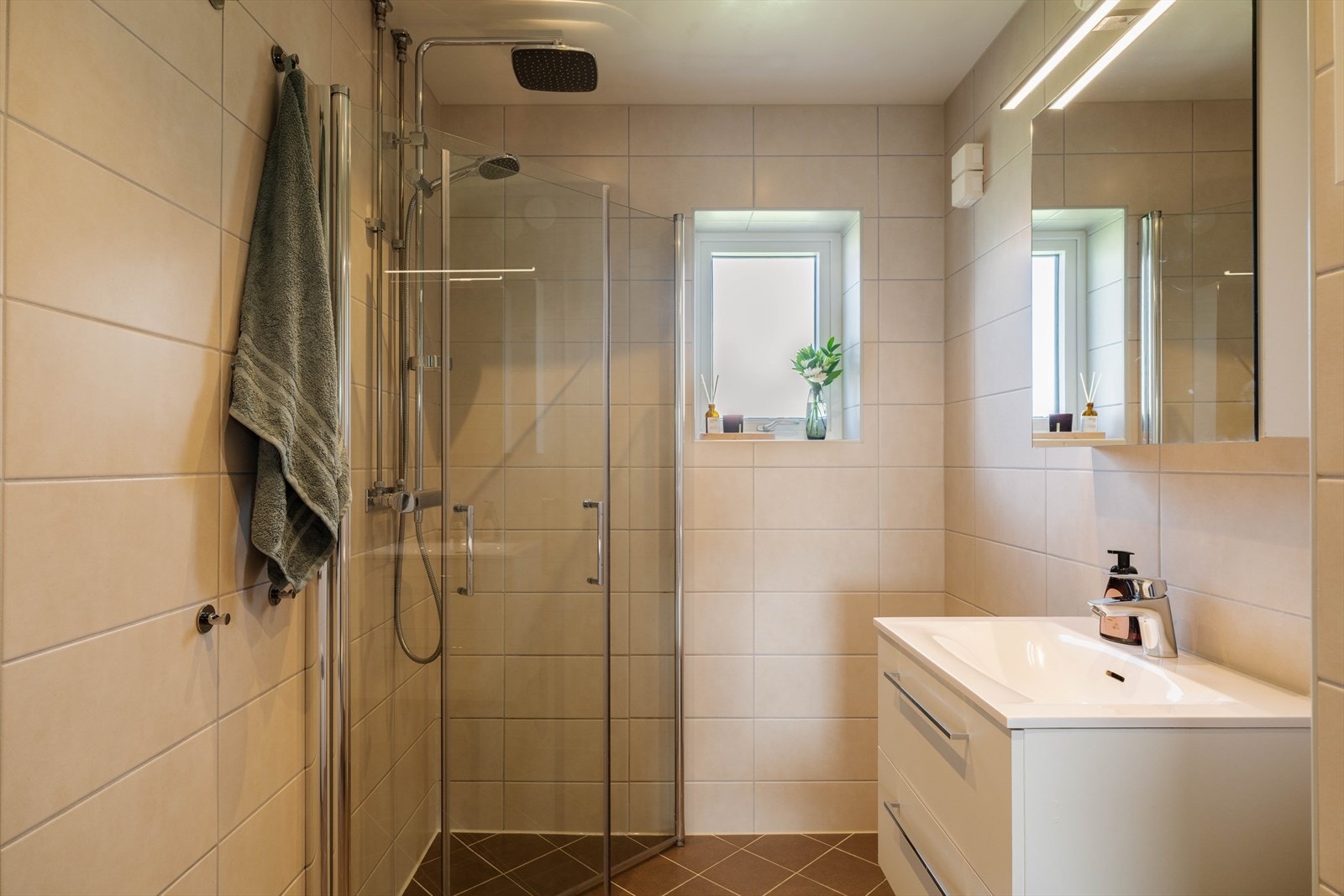 Badet er innredet med klosett, romslig dusjhjørne, servant med underskuffer og overspeil med belysning. Galleribilde