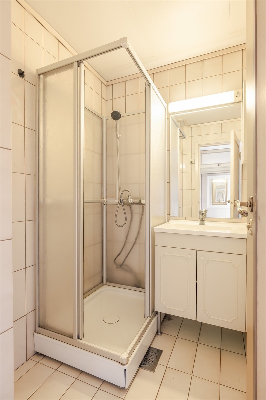 Flislagt bad med dusjkabinett og baderomsinnredning med underskap og heldekkende servant. Speil og lys med elektrisk uttak i overkant av servanten. Badet har behov for oppgradering for å tilfredsstille dagens krav til standard. Galleribilde