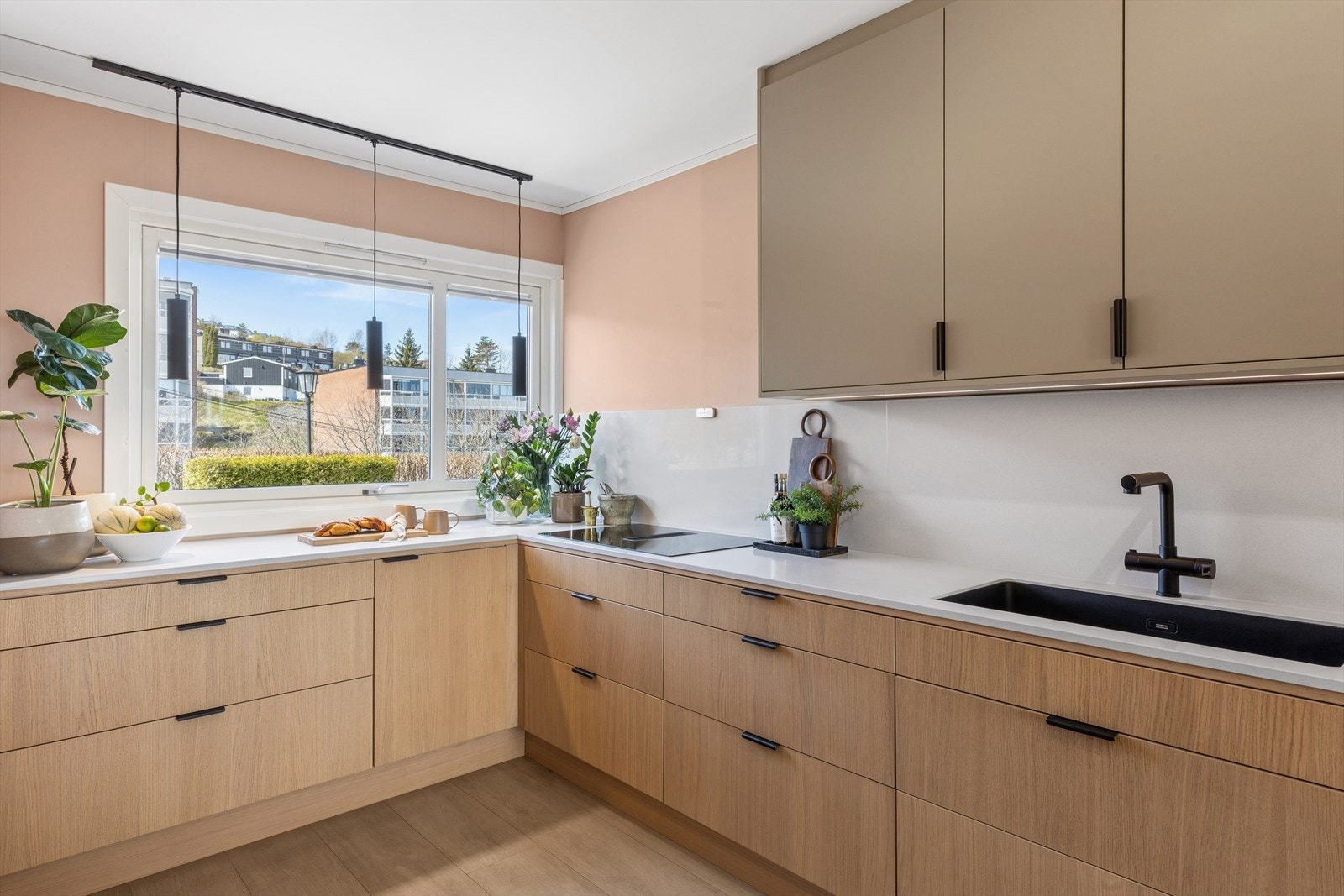 Kjøkkeninnredningen har en kombinasjon av slette fronter i trestruktur og beige, med en slitesterk benkeplate. Galleribilde