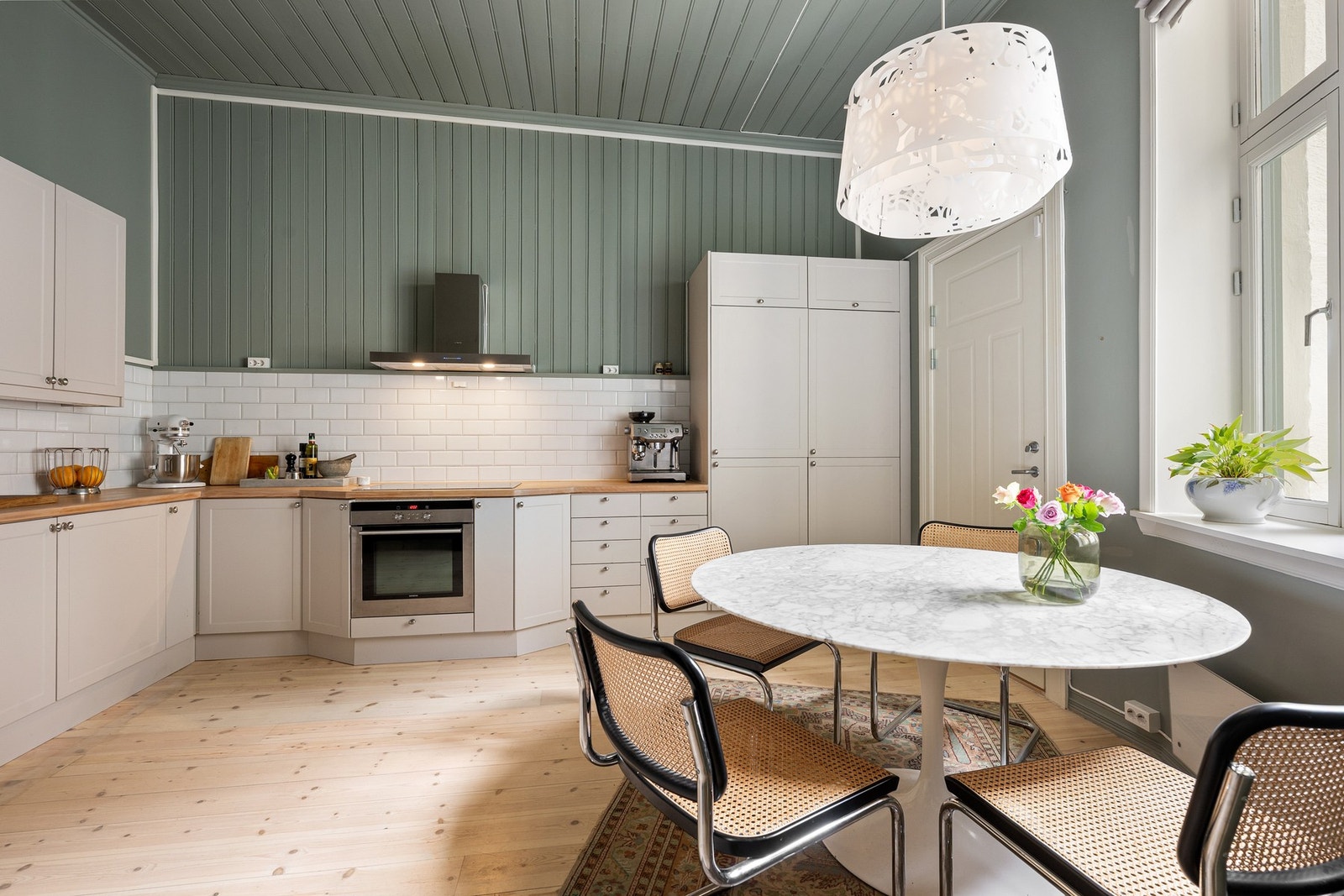 Fliser på vegg over benkeskap. Heltre benkeplate med nedfelt kum i rustfritt stål. Induksjonstopp, stekeovn og kjøl/frys er integrert i innredningen. Galleribilde
