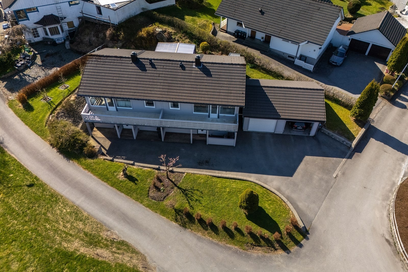 Flott opparbeidet tomt med asfaltert gårdsrom, terrasse, hage med plen og diverse beplantning. Galleribilde