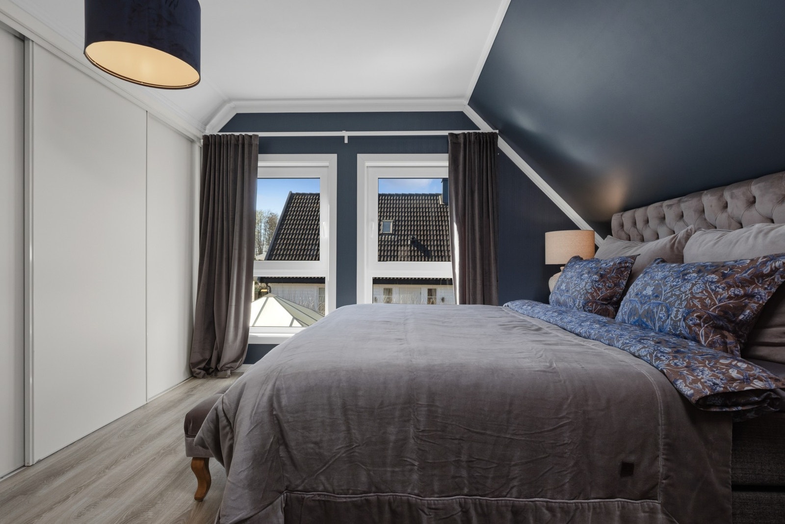Soverom i loftetasje, plass til dobbeltseng, nattbord på begge sider og oppbevaring i skyvedørs garderobe langs vegg. Store vindusflater slipper inn rikelig med naturlig lys. Galleribilde