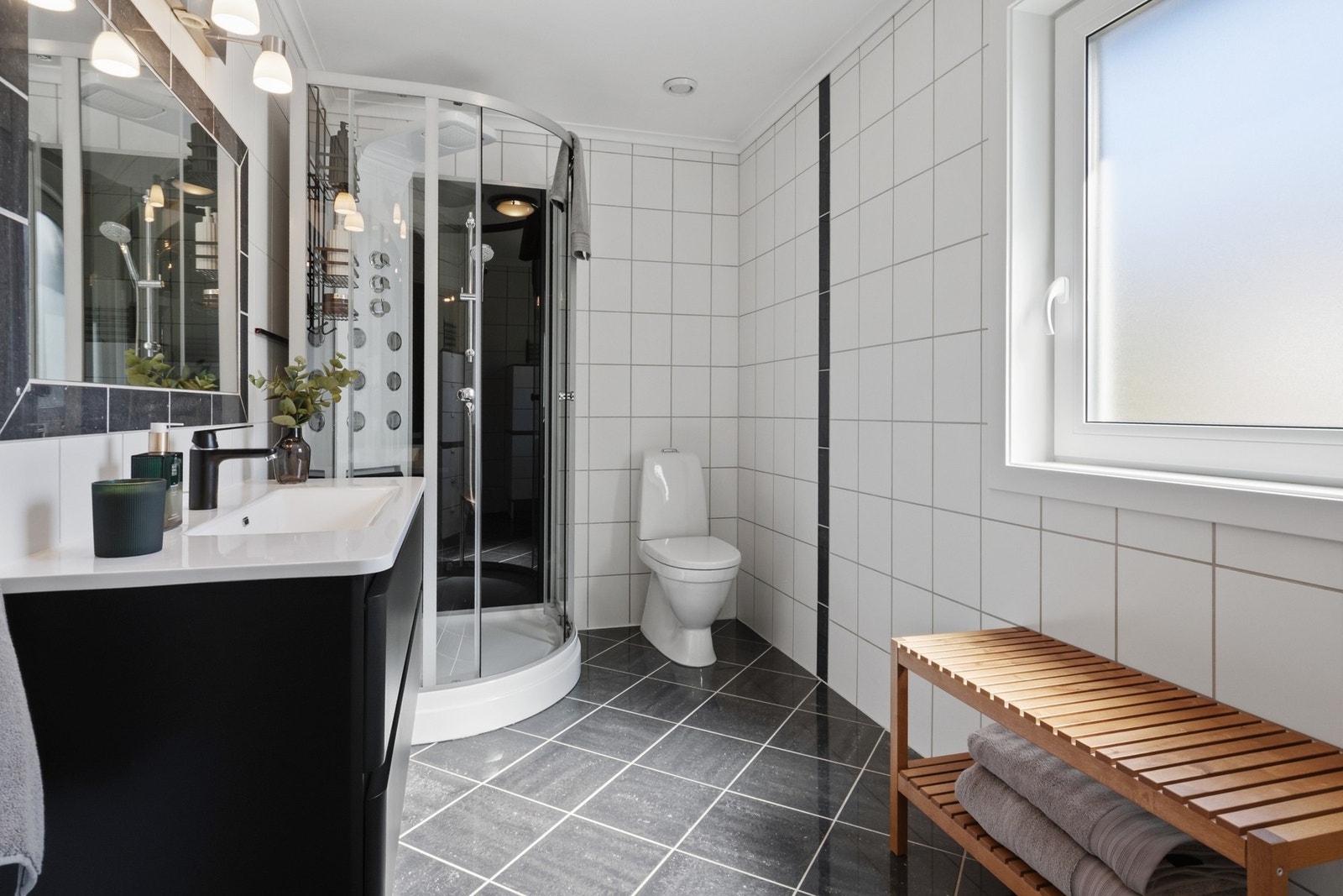 Badet i 1. etasje har oppgraderte overflater fra 2007. Rommet er flislagt og har elektriske varmekabler i gulv. Det er innredning med servant, dusjkabinett og toalett. Galleribilde