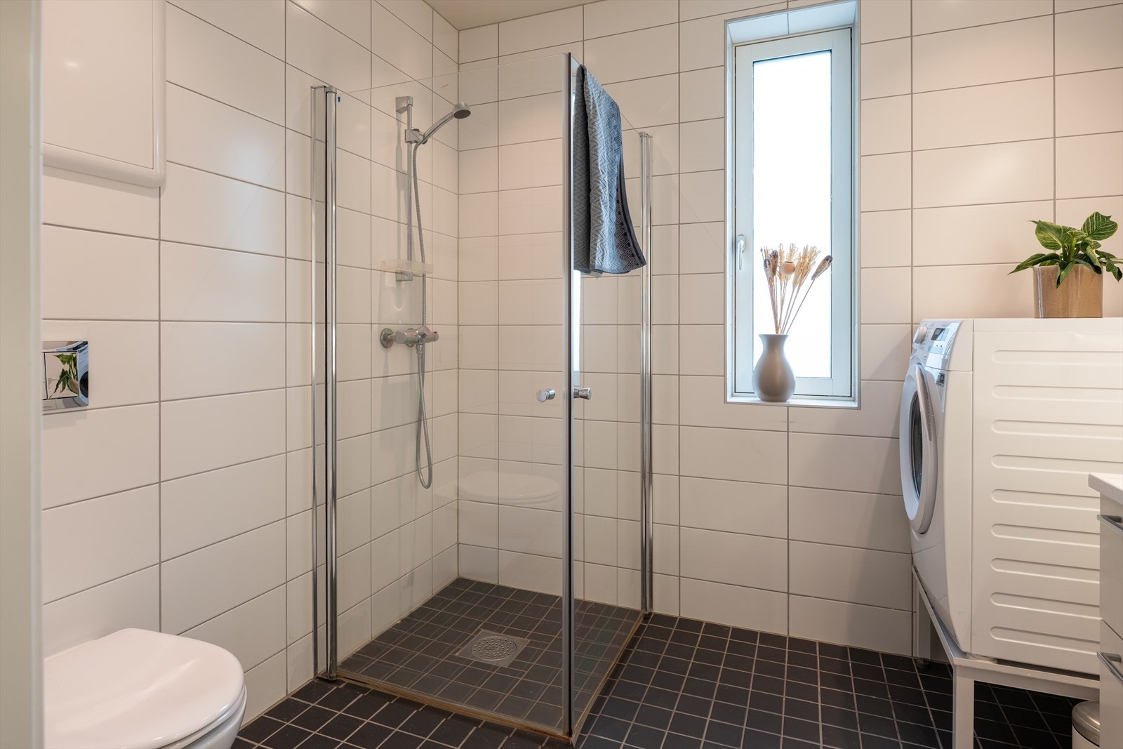 Videre byr badet på dusjhjørne med dører, vegghengt toalett og opplegg for vaskemaskin. Galleribilde