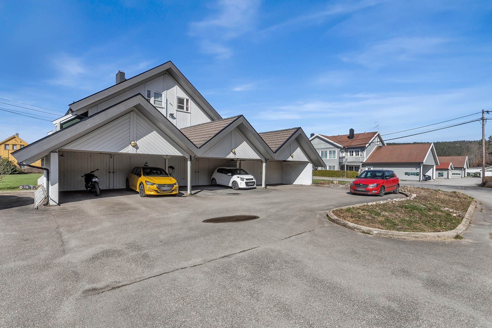 Parkering i carport med tilhørende bod og elbillader. Galleribilde