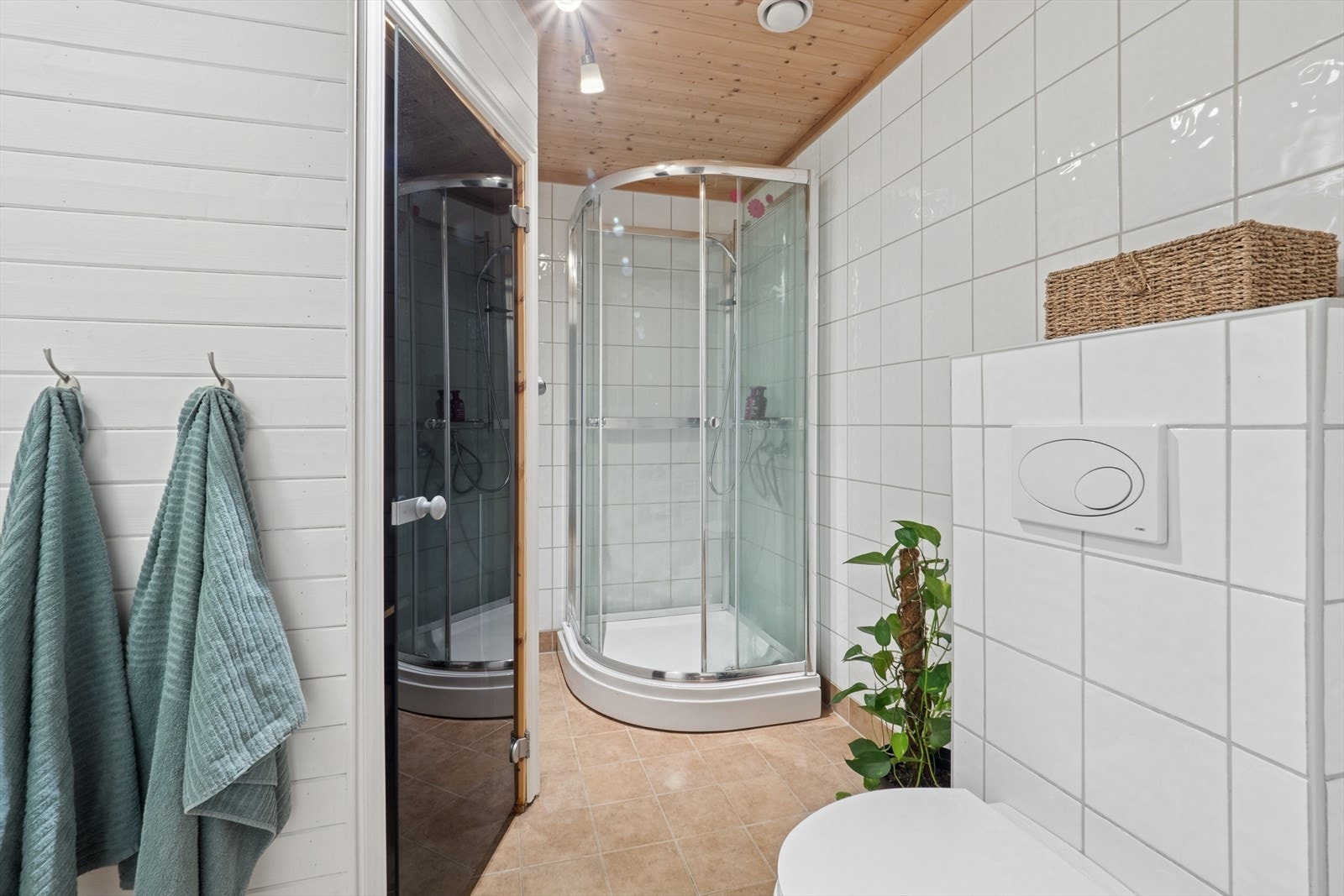 Badet i 2. etasje har fliser og panel på veggene og fliser på gulv. Badet er innredet med servant med underskap, dusjkabinett og vegghengt wc. Galleribilde