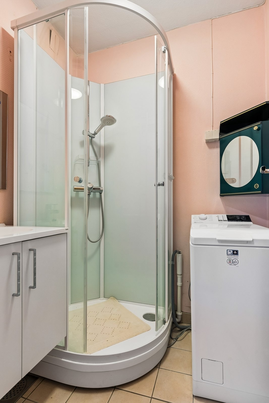 Badet har flislagt gulv. Servantinnredning fra 2022. Her er det dusjkabinett og opplegg for vaskemaskin. Galleribilde