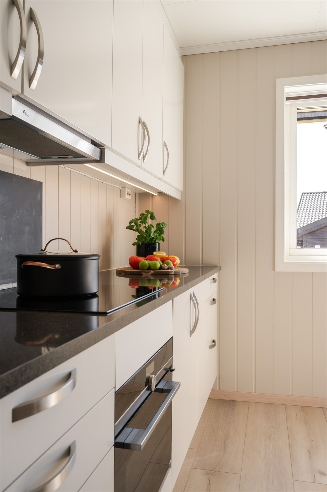 Praktisk med plater i benkeryggen ved platetoppen og oppvaskkummen, samt takhøye overskap med belysning under. Galleribilde