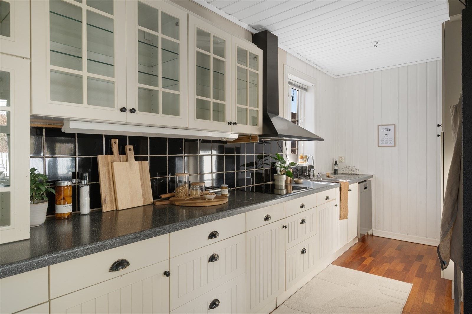 Kjøkkenet fremstår som moderne og stilrent, med en gjennomført innredning. Innredningen har profilerte fronter og vitrineskap, kombinert med laminat benkeplate. Galleribilde
