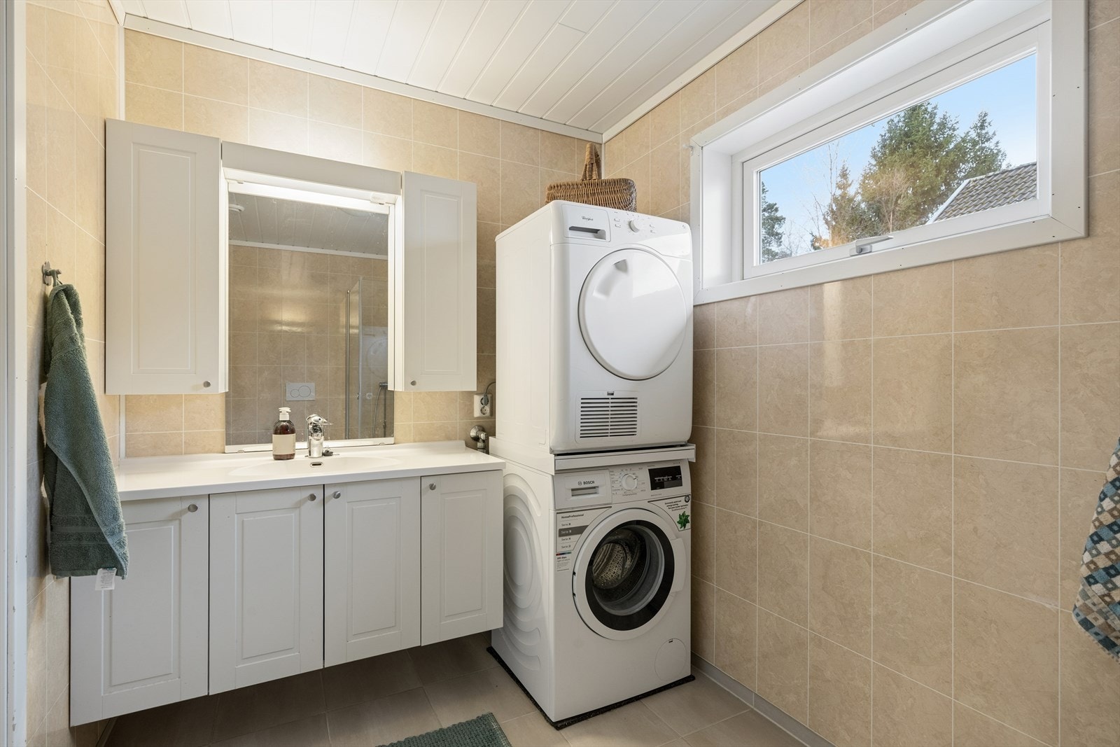 Det andre badet fungerer også som vaskerom, med flislagt gulv med varmekabler og opplegg for vaskemaskin. Galleribilde