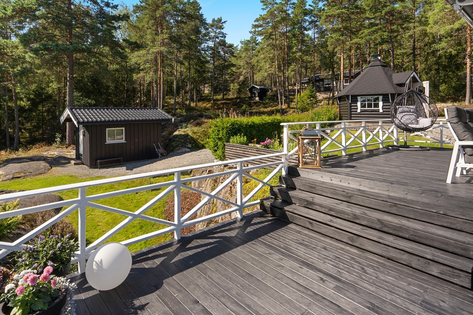 Fra verandaen ser man over til annekset og grillhytta. Galleribilde