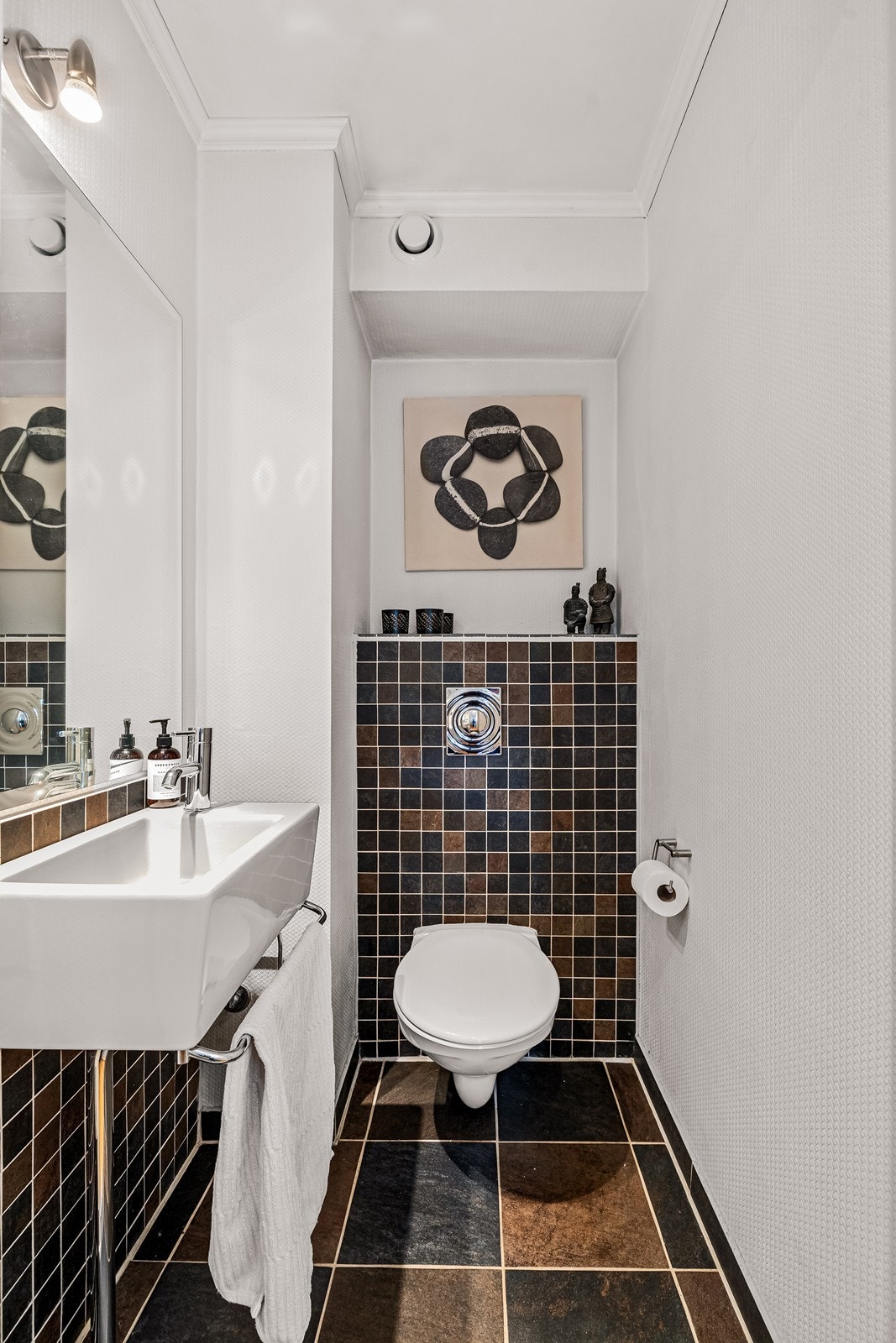 Toalettrommet har samme flis som bad på gulv og delvis mosaikkflis på vegg, innredet med toalett og servant. Galleribilde