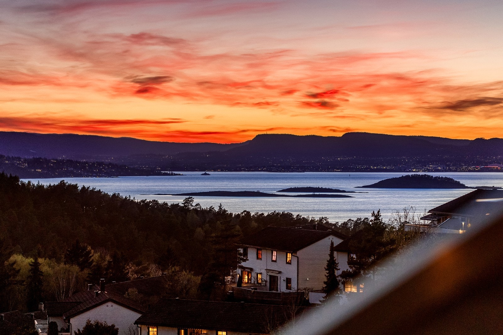 Det vakre fargespillet på himmelen mot lysene i det fjerne og fjorden gir et nesten magisk uttrykk. Galleribilde