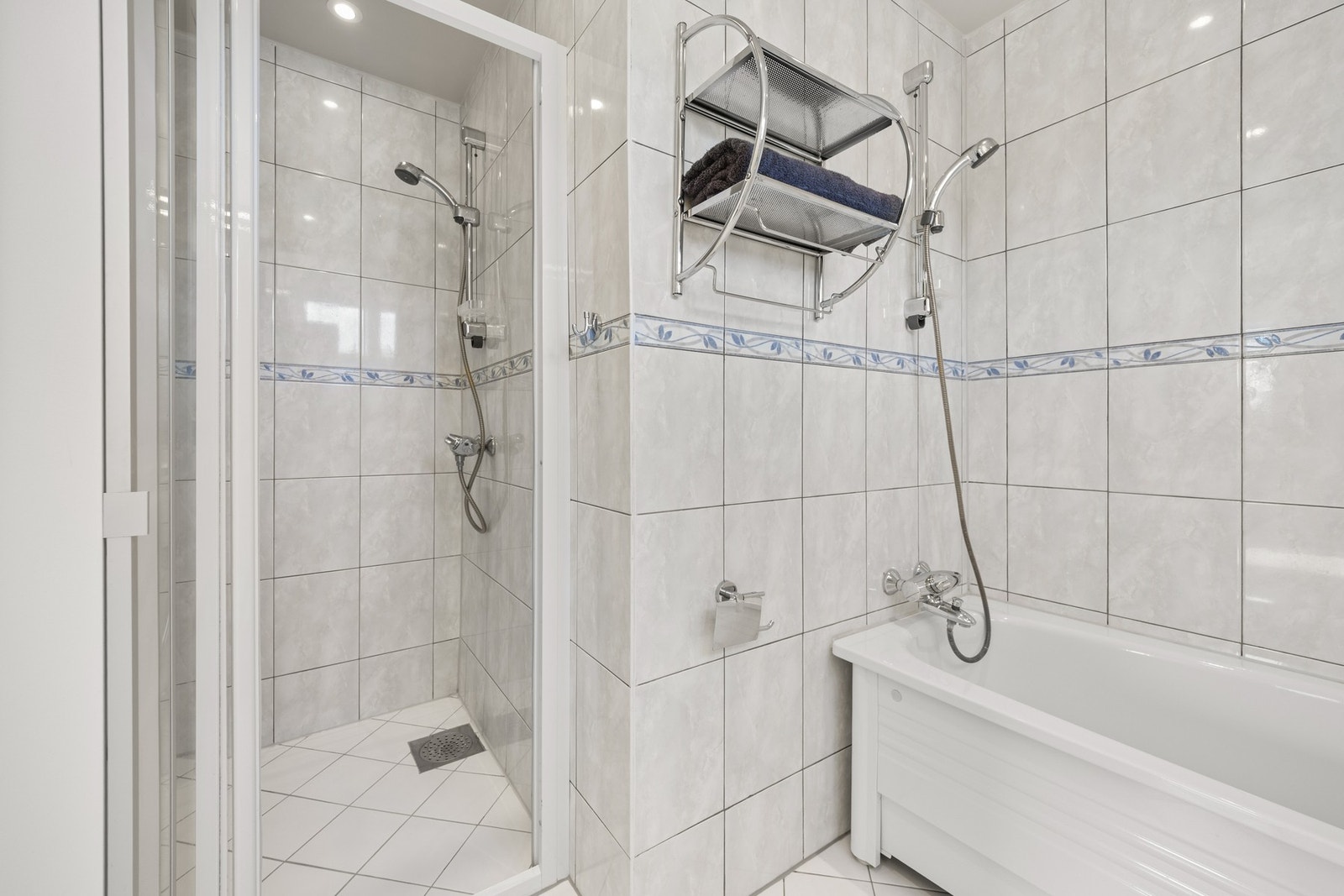Badet er innredet vegghengt toalett, dusjsone, badekar, servantskap med nedfelt servant og veggskap. Galleribilde
