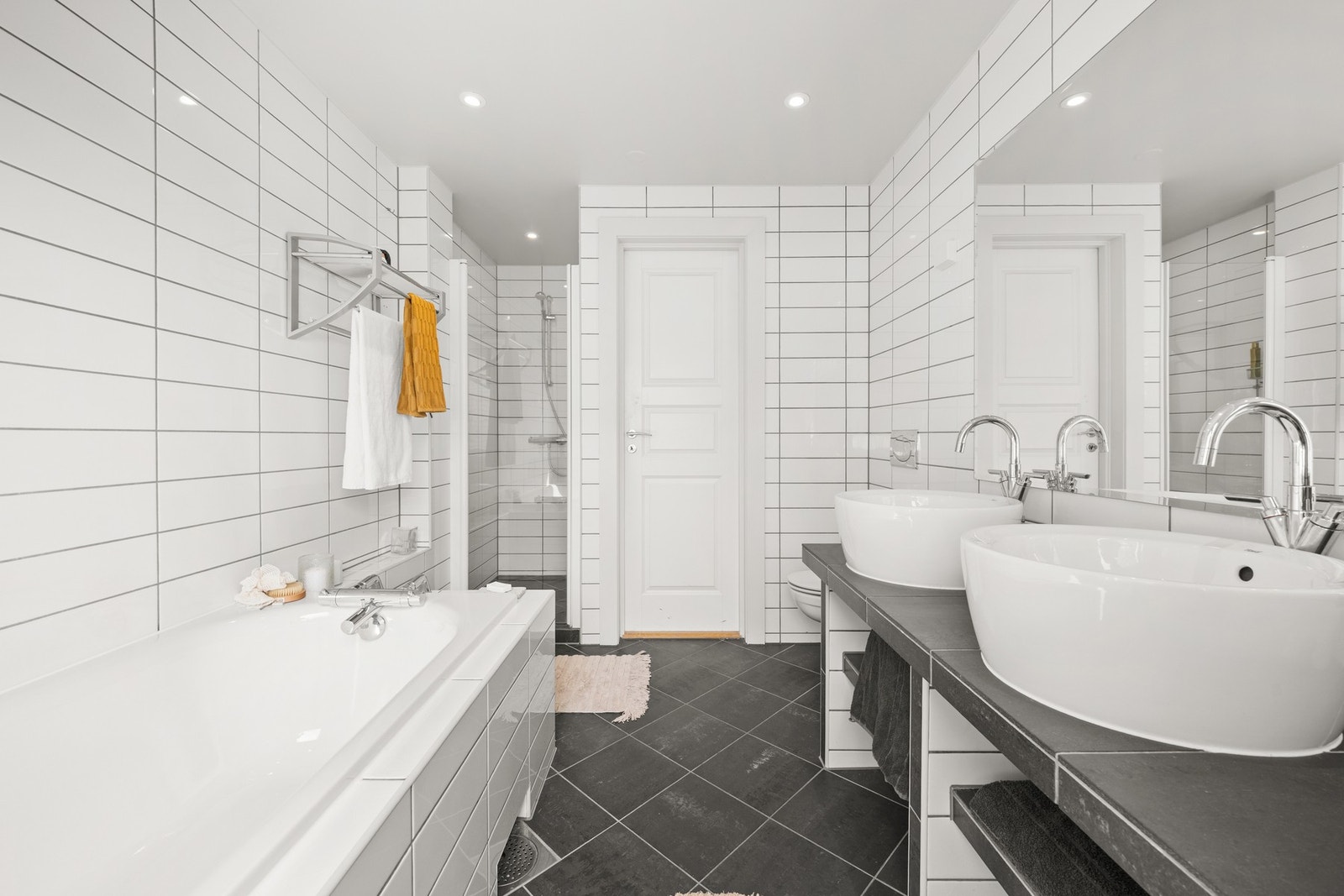 Badet består av badekar, dusjnisje, vegghengt toalett og dobbel servant. Galleribilde