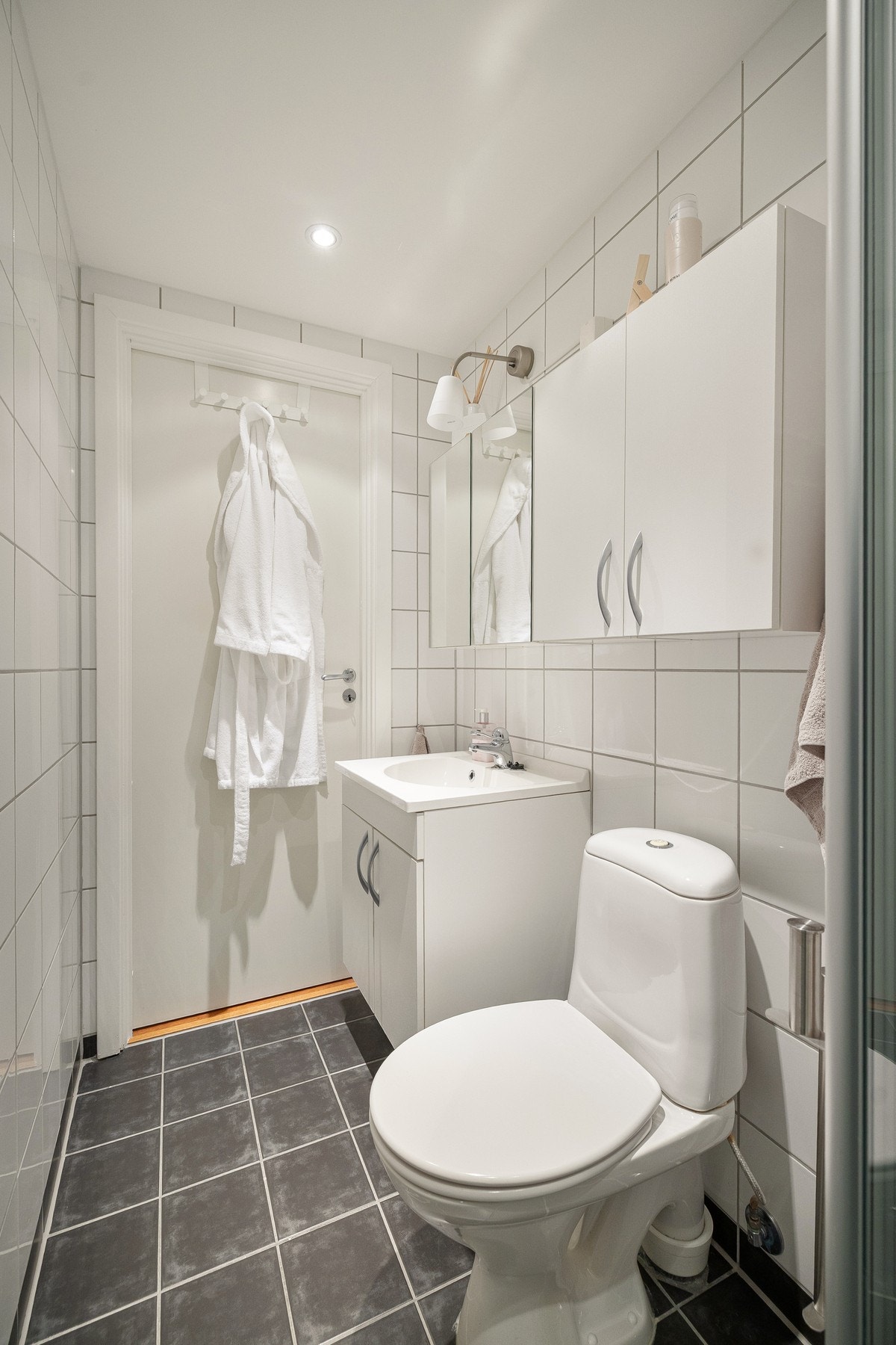 Badet er utstyrt med dusjhjørne, skapinnredning med nedfelt servant og toalett. Galleribilde