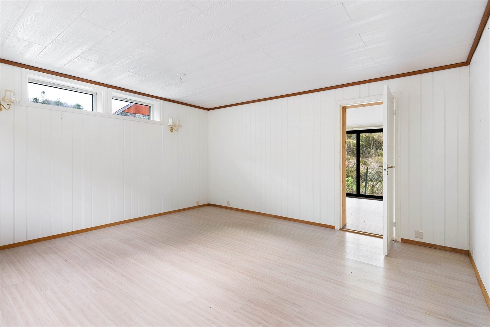 Gulv med laminat og vegger med panel gir en praktisk overflate i stuen. Galleribilde