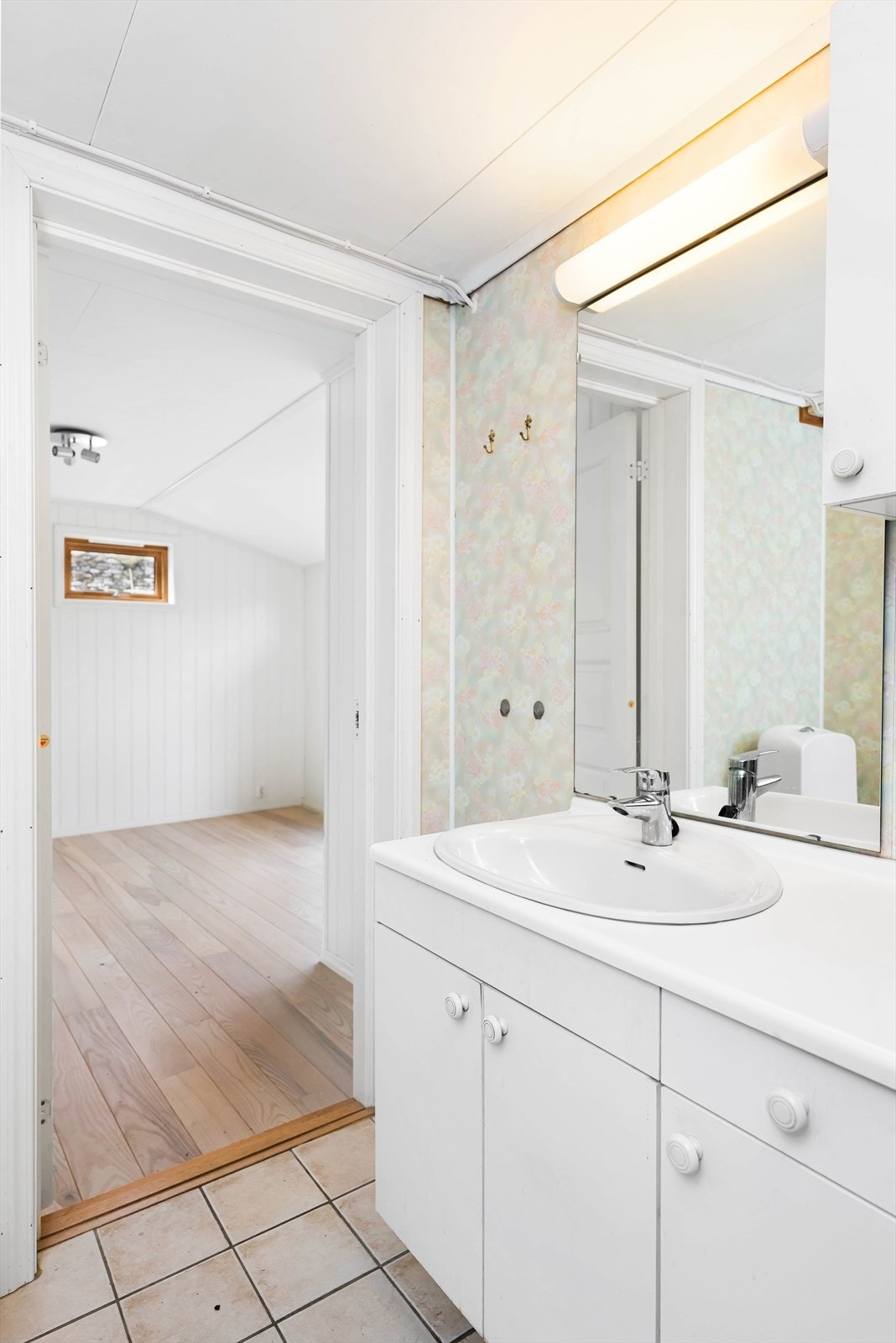 Badet har en eldre innredning med servant og speilskap, samt gulv med fliser og baderomsplater på vegger. Galleribilde