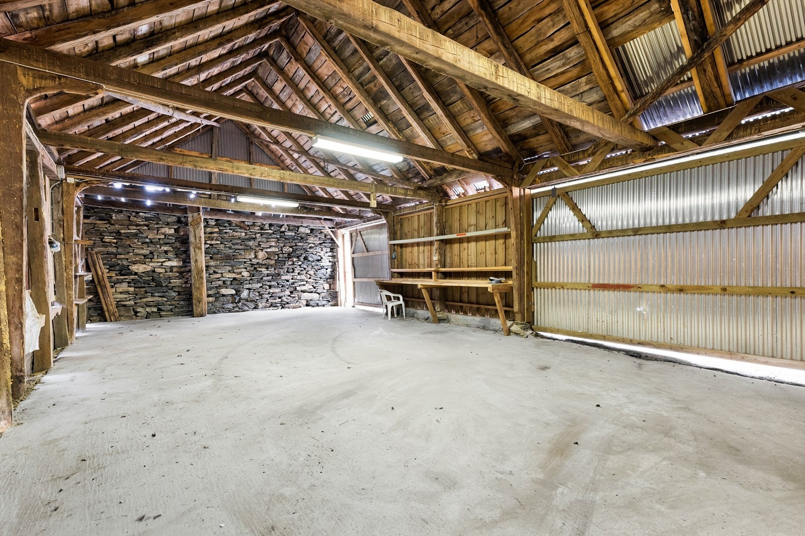 Innvendig har løen et åpent rom med synlige trekonstruksjoner og en stablet steinvegg. Her har man god plass for oppbevaring eller hobby. Galleribilde