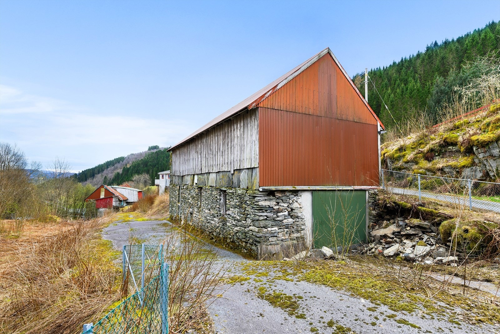 Løens bakside har en synlig grunnmur av naturstein og trevegger med bølgeblikkpanel. Herfra er inngang stort lagerrom i underetasjen. Galleribilde