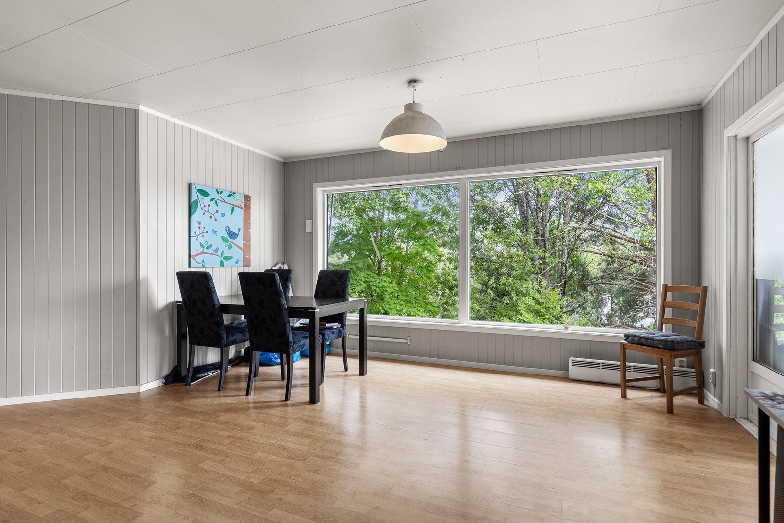 Pen stue, med panelvegger og store vinduer som gir masse lys. Galleribilde