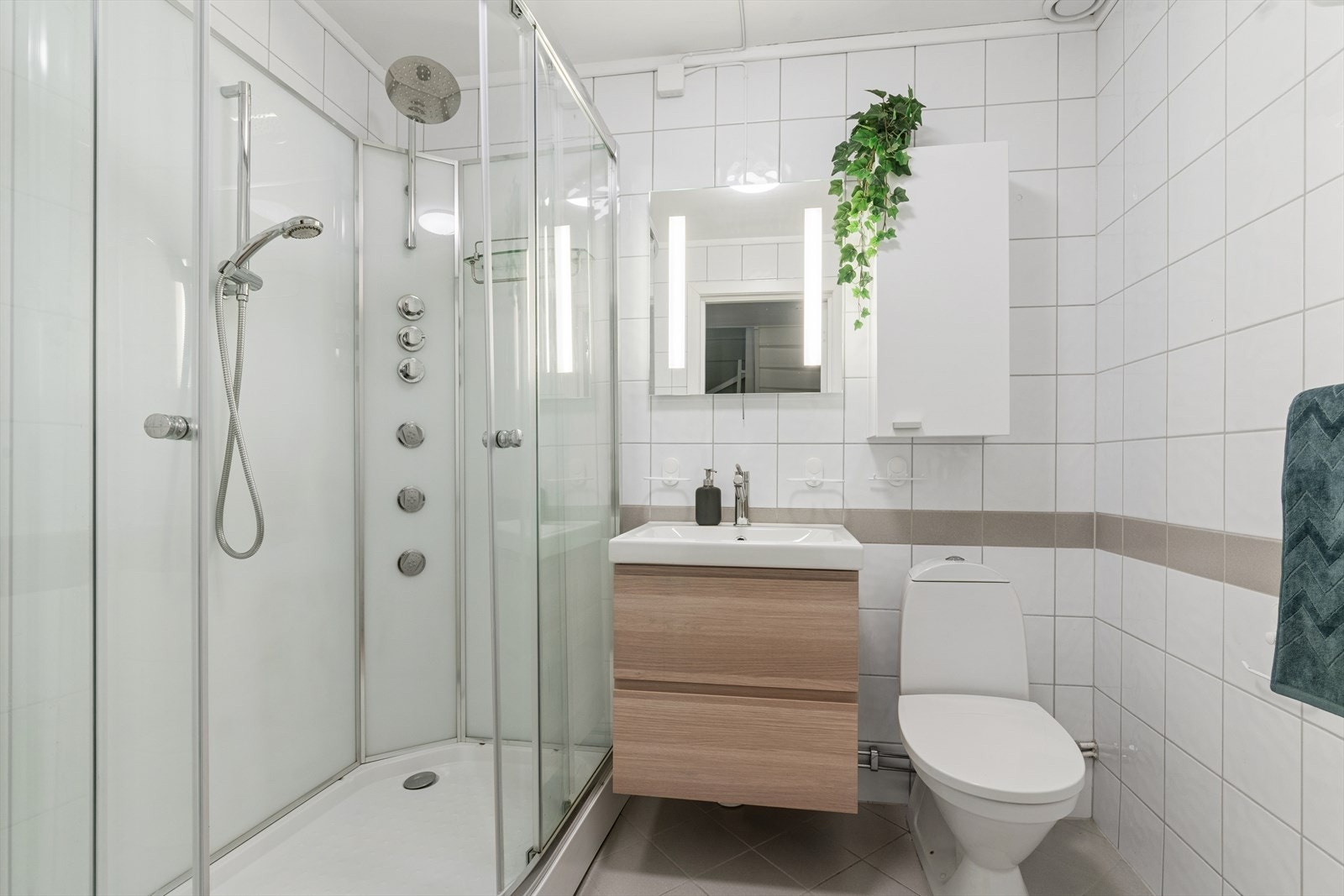 Lyst baderom med flislagte gulv og vegger, med varmekabler i gulvet. Rommet har innredning med nedfelt servant, toalett og dusjkabinett. I tillegg til baderom, har du et eget vaskerom i u.etg., samt tre boder. Galleribilde