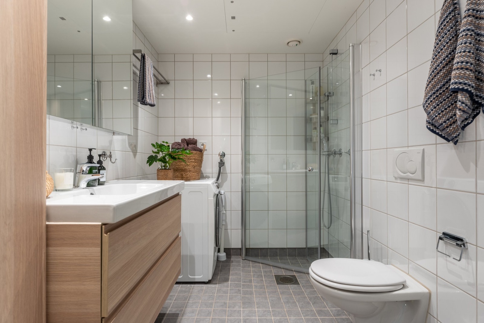 Delikat helfliset bad med gulvvarme og downlights i himling. Det er nisje for vaskesøyle med plass for både vaskemaskin og tørketrommel. Galleribilde
