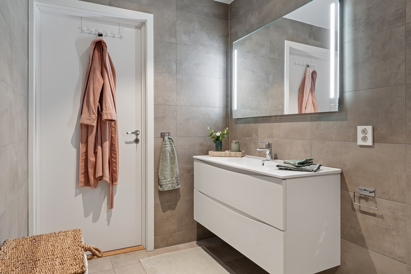 Badet i 2. etasje fremstår som moderne og funksjonelt, med flislagte vegger og gulv i tidløse materialvalg som gir et helhetlig og stilrent uttrykk. Taket er innfelt med downlights som gir behagelig belysning. Gulvet har elektriske varmekabler Galleribilde